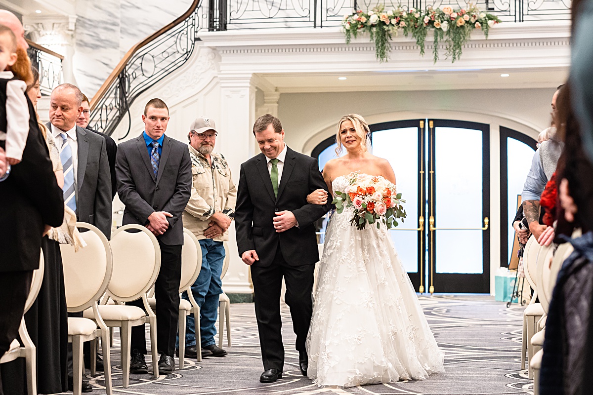 The bride crying as her dad walks her down the aisle at her the ceremony at The Virginian Hotel in Lynchburg, Virginia.