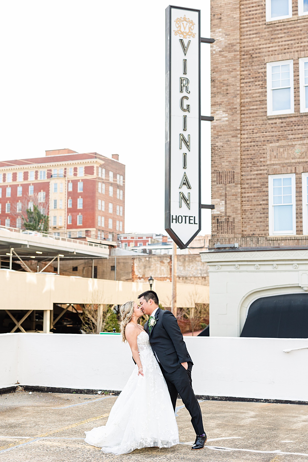 Portrait of the bride and groom in front of the sign of The Virginian Hotel in Lynchburg, Virginia.