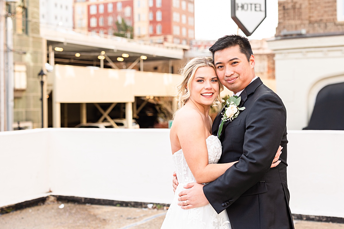 Portrait of the bride and groom in front of the sign of The Virginian Hotel in Lynchburg, Virginia.