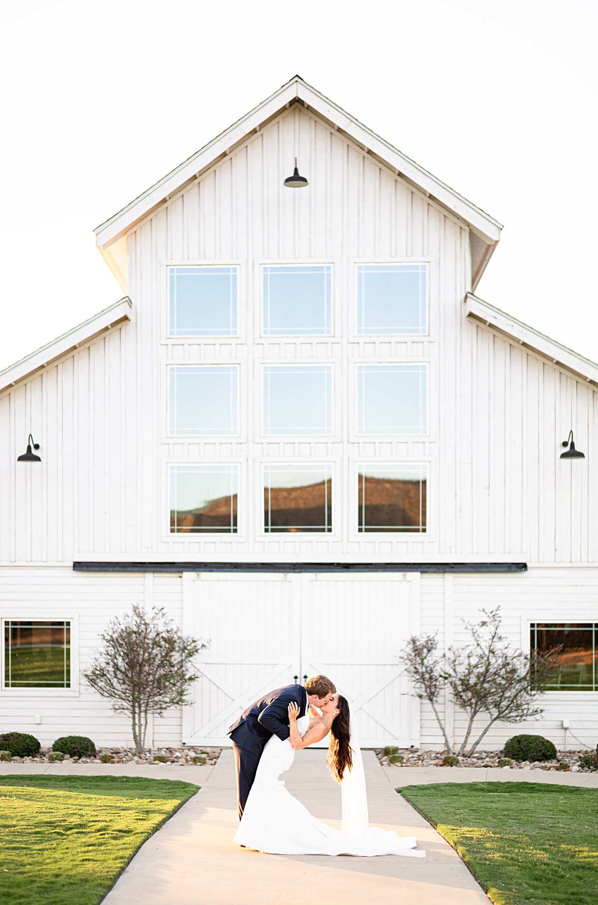 Bride and Groom sharing a kiss in front of their venue Sabrina Cedars in Abilene, Texas.